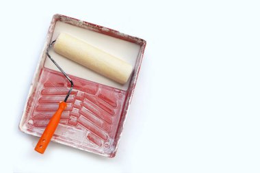 Beyaz arka plandaki boya tepsisinde boya silindiri.