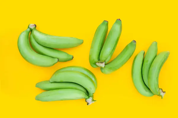 Green banana on yellow background