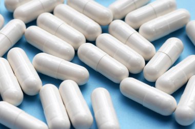 Mavi arkaplan üzerindeki ilaç kapsülleri.