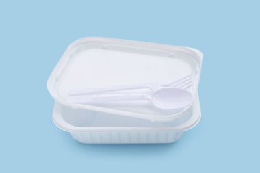 Mavi arka planda çatal ve kaşıkla plastik yiyecek kutuları..
