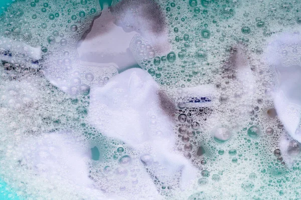 Suya batırılmış kirli beyaz çoraplar, mavi leğende çözünen deterjan..