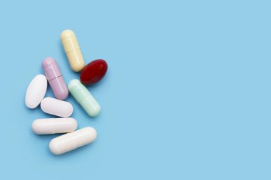 Mavi arka planda renkli kapsüller ve haplar.