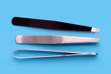 Tweezers on blue background. Copy space