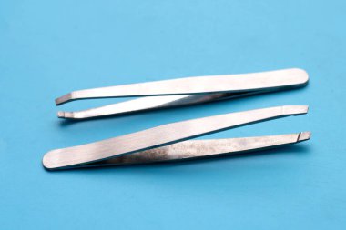 Tweezers on blue background. Copy space