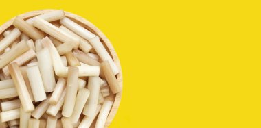 Sarı zemin üzerinde taze nilüfer kökü.