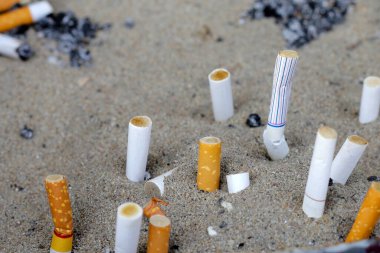 Cigarettes and ash on dirty sand in trash tray