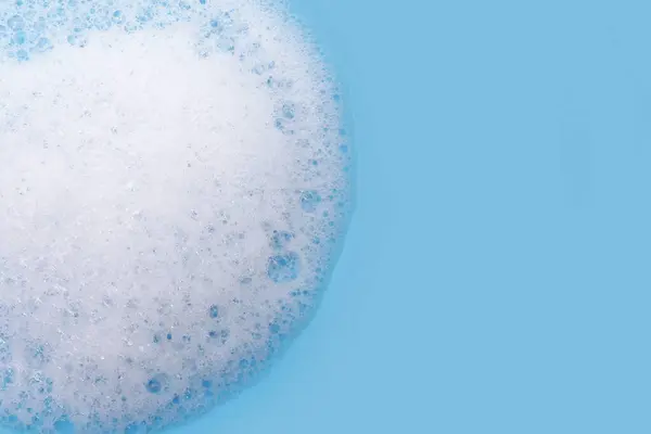 White soap suds foam bubble on blue background.