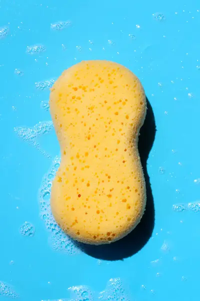 Yellow sponge with bubbles on blue background