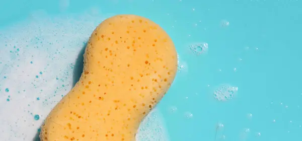 Yellow sponge with bubbles on blue background