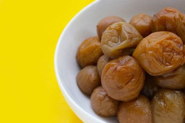 Sarı arka planda turşulu erikler.