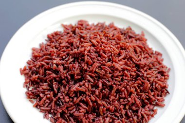 Koyu arkaplanda beyaz tabakta siyah böğürtlen pilavı..