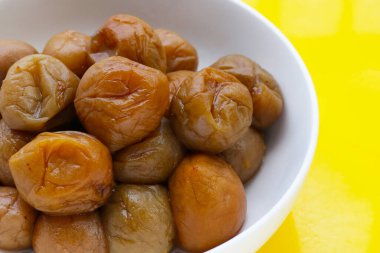 Sarı arka planda turşulu erikler.