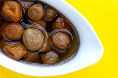 Sarı arka planda turşulu erikler.