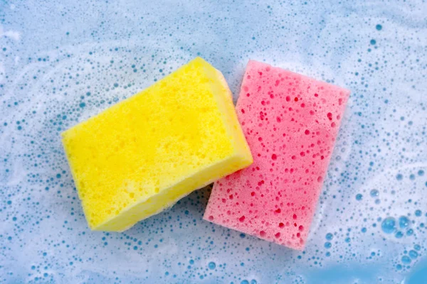 Cleaning sponges in foam of dishwashing liquid. Washing dishes concept