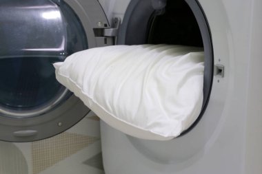 Çamaşır makinesinde beyaz yastık.