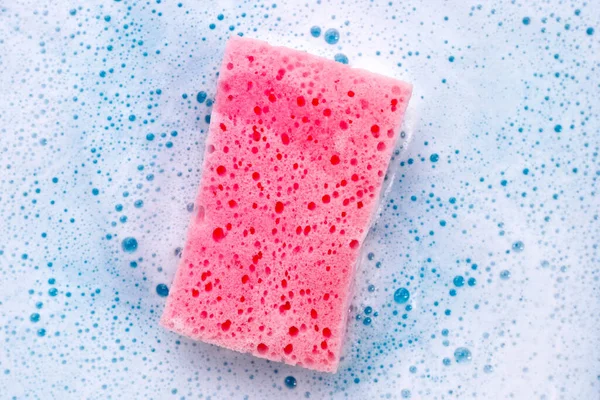 Cleaning sponge in foam of dishwashing liquid. Washing dishes concept