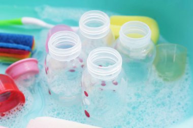 Bebek şişelerini plastik mavi leğende yıka.