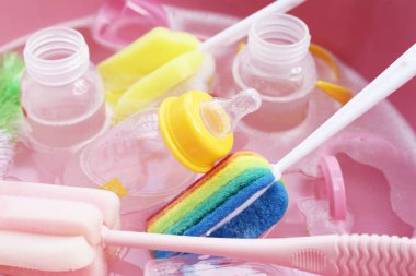 Bebek şişelerini plastik pembe leğende yıka.