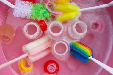 Bebek şişelerini plastik pembe leğende yıka.