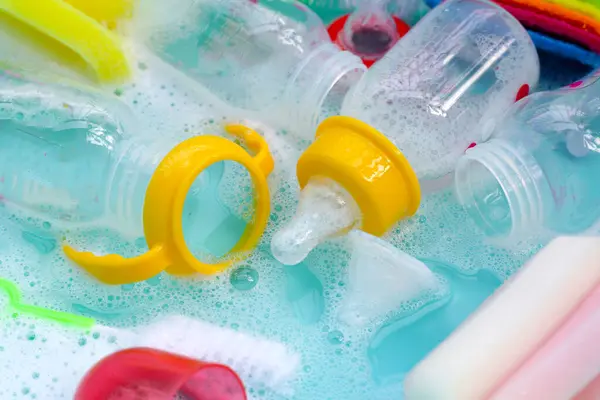 Wash baby bottles in plastic blue basin