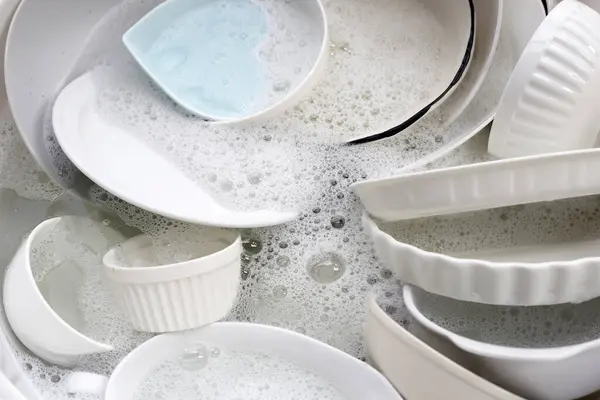 Dish washing, Dirty dishes soaking in kitchen sink.