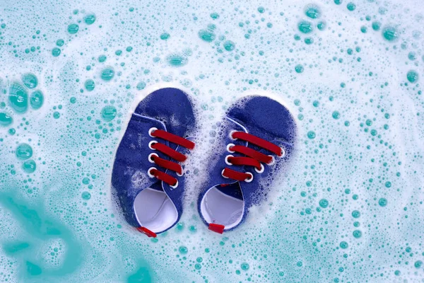 Bebek ayakkabılarını yıkamadan önce çamaşır deterjanıyla ıslat. Çamaşır konsepti, Üst Görünüm