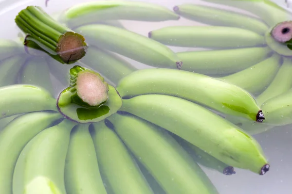 Raw green bananas soaking the bananas in water. Cleaning fruits