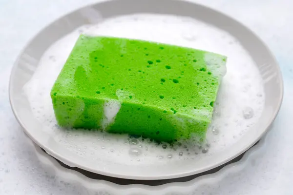 Plate with cleaning sponge in foam of dishwashing liquid. Washing dishes concept