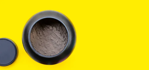 Whey protein powder in plastic container on yellow background.
