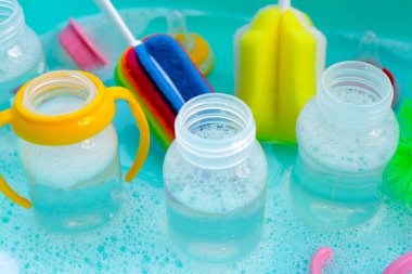 Bebek şişelerini plastik mavi leğende yıka.