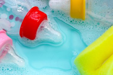 Bebek şişelerini plastik mavi leğende yıka.