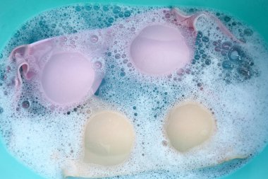 Beyaz köpüklü, çözünmüş deterjana batırılmış kadın sütyeni. Çamaşır konsepti