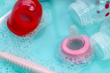 Bebek şişelerini plastik mavi leğende yıka.