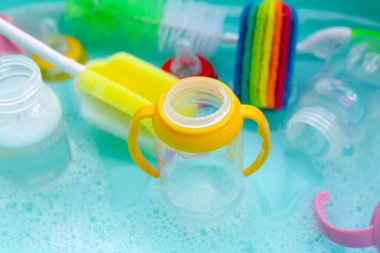 Bebek şişelerini plastik mavi leğende yıka.