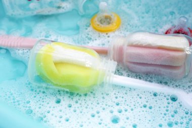 Bebek şişelerini plastik mavi leğende yıka.