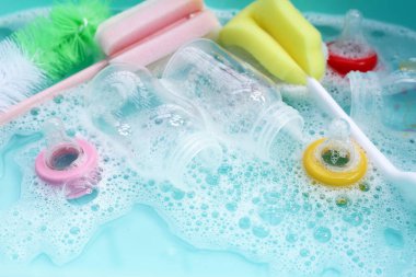 Bebek şişelerini plastik mavi leğende yıka.