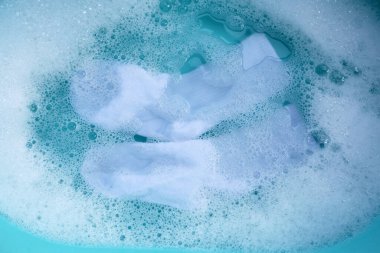 Kirli çoraplar suya batırılmış, deterjanı leğende eritiyor..