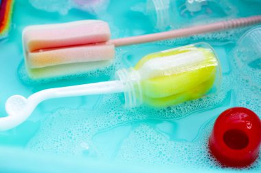 Bebek şişelerini plastik mavi leğende yıka.