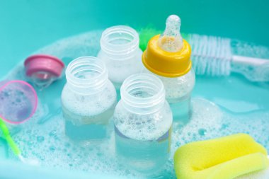 Bebek şişelerini plastik mavi leğende yıka.