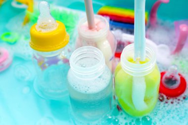 Bebek şişelerini plastik mavi leğende yıka.