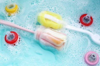 Bebek şişelerini plastik mavi leğende yıka.