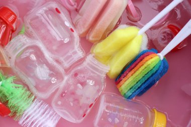 Bebek şişelerini plastik pembe leğende yıka.