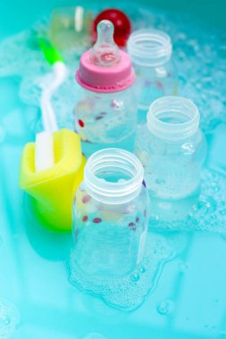 Bebek şişelerini plastik mavi leğende yıka.