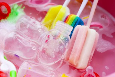 Bebek şişelerini plastik pembe leğende yıka.