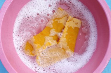 Kirli çoraplar suya batırılmış, deterjanı leğende eritiyor..