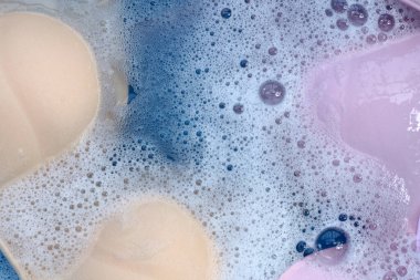 Beyaz köpüklü, çözünmüş deterjana batırılmış kadın sütyeni. Çamaşır konsepti