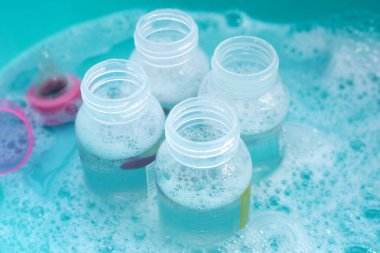 Bebek şişelerini plastik mavi leğende yıka.