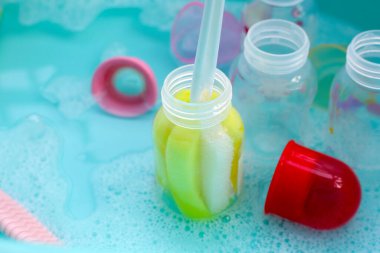 Bebek şişelerini plastik mavi leğende yıka.