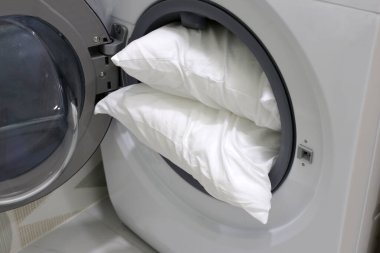 Çamaşır makinesinde beyaz yastık.