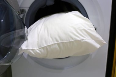 Çamaşır makinesinde beyaz yastık.